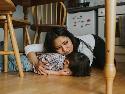 Una mujer consuela a un pequeño niño, en su hogar.