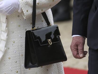 Isabel II, reina de Inglaterra, con su inseparable Launer, un Traviata de charol negro.