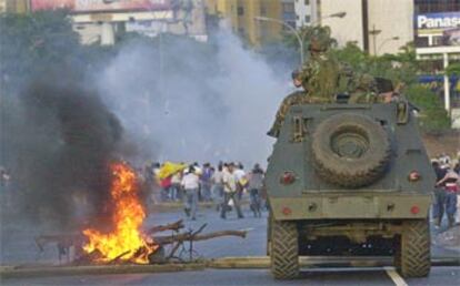 Una tanqueta de la Guardia Nacional avanza sobre una barricada levantada frente a la sede de Petróleos de Venezuela en Caracas.