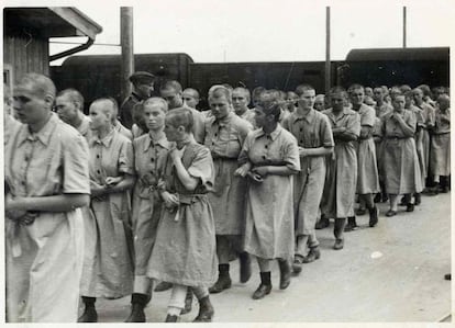Prisioneras entran dentro del campo de mujeres, ya con el uniforme de prisioneros bajo la mirada de un guardia SS.