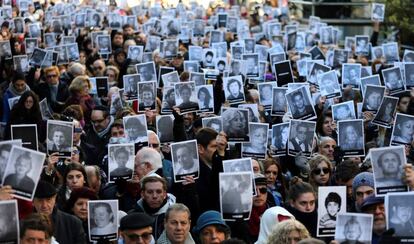 Los presentes en el acto muestran las fotos de las v&iacute;ctimas.