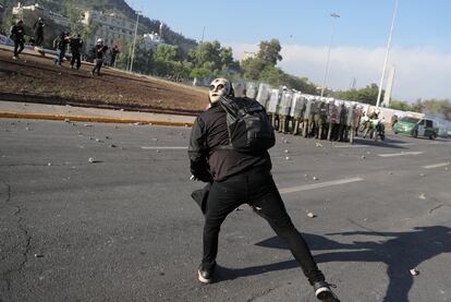 Un manifestante lanza un objeto a un grupo de policías con equipamiento anti-disturbios, en Santiago de Chile.