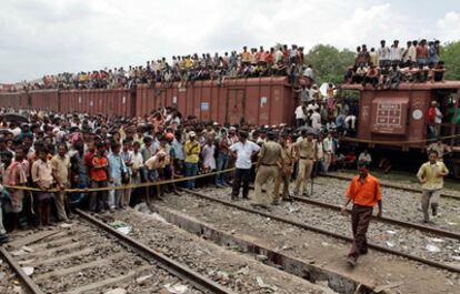 Numerosos curiosos se agolpan en la estación de Sainthia, donde los equipos de rescate intenta sacar a víctimas de los amasijos de hierro de los trenes accidentados.