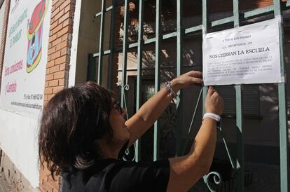 Una empleada coloca un cartel en la entrada de la Escuela Infantil El Tambor en San Fernando de Henares en noviembre avisando del cierre y traslado inminente.