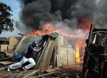 Un surafricano trata de quemar una chabola en un asentamiento de Johanesburgo.