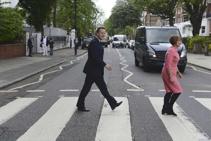 El primer ministro británico David Cameron cruza el paso de peatones frente a los estudios de Abbey Road junto con la exministra Tessa Jowell, en Londres.