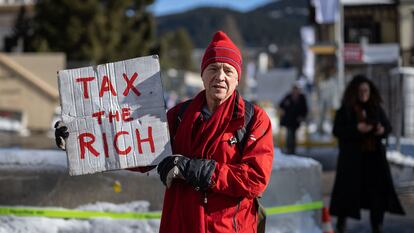 El millonario británico Phill White posa con un cartel en el que se lee "Tax the rich" (graven a los ricos en inglés) a las afueras de la reunión anual del Fondo Económico Mundial en Davos (Suiza), en enero de 2023.