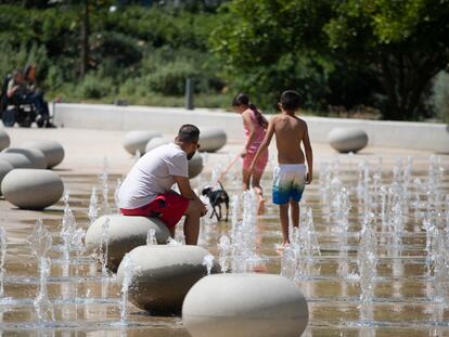 Diversas personas se refrescan con unos surtidores en un parque en el barrio de Sant Andreu de Barcelona, este sábado.
