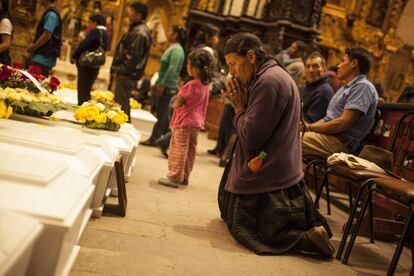 Una mujer reza frente a los féretros de sus familiares durante una misa en la Catedral de Huamanga (Perú).