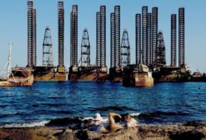 Unos trabajadores de una plataforma petrolífera tomando el sol en una playa bañada por el mar Caspio cerca de Baku, la capital de Azerbaiyán. EFE/Archivo