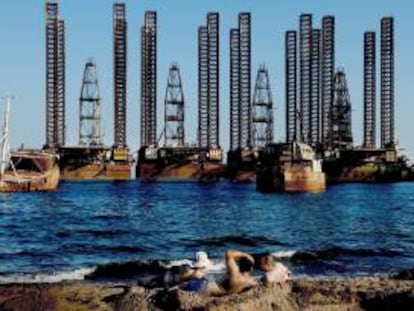 Unos trabajadores de una plataforma petrolífera tomando el sol en una playa bañada por el mar Caspio cerca de Baku, la capital de Azerbaiyán. EFE/Archivo
