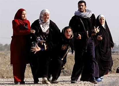 Cuatro mujeres iraquíes y un hombre esperan a sus seres queridos en el exterior de la prisión de Abu Graib.