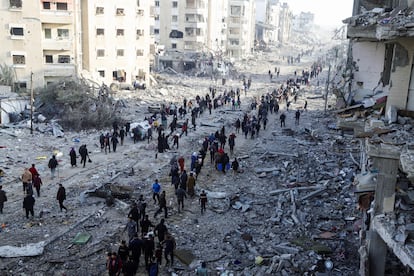 Desplazados palestinos se abren paso entre los escombros mientras tratan de regresar a sus hogares en el norte de la franja de Gaza, este domingo.