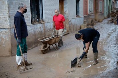 Voluntarios y vecinos retiran fango de una calle de Paiporta