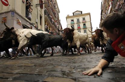 Un corredor permanece en el suelo al paso de los toros durante el cuarto encierro de San Fermín.