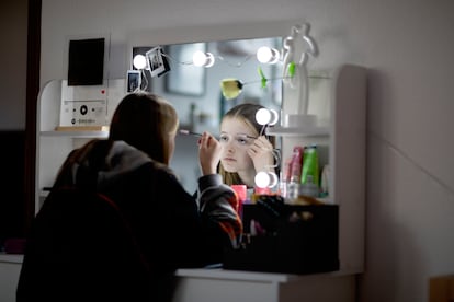 Una joven se maquilla frente a un espejo.
