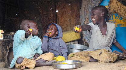 Los hermanos ugandeses Rahim, Emmanuel y lobuka (de izquierda a derecha) disfrutan de una comida en el campo de Bidi bidi, en el noroeste de Uganda, en 2022.