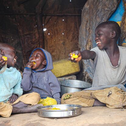 Los hermanos ugandeses Rahim, Emmanuel y lobuka (de izquierda a derecha) disfrutan de una comida en el campo de Bidi bidi, en el noroeste de Uganda, en 2022.