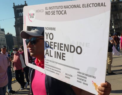 Un manifestante sostiene una pancarta que asemeja una credencial electoral del INE.