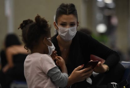 Una mujer y una niña con mascarilla en el aeropuerto Galeão de Río de Janeiro.