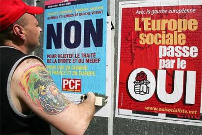 Un hombre pega un cartel del Partido Comunista a favor del <i>no</i> junto a uno socialista a favor del <i>sí.</i>