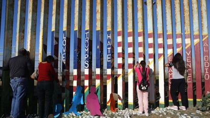 Migrantes frente a la valla fronteriza de Tijuana.