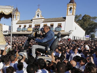 Un peregrino en una silla de ruedas motorizada es alzado por la multitud para poder aproximarse a la virgen del Rocío, en Almonte, Huelva (España).