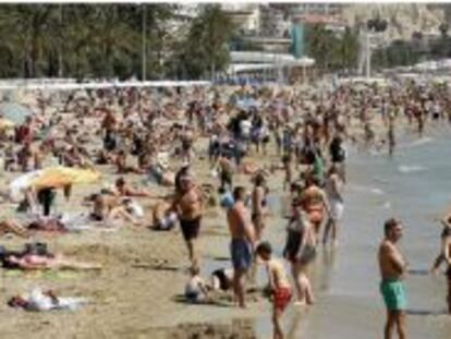 Miles de turistas disfrutan de una soleada jornada en la playa del Postiguet de Alicante, durante el Domingo de Ramos.