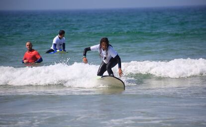 Una de las asistentes al festival aprende a hacer surf ante la mirada del instructor.