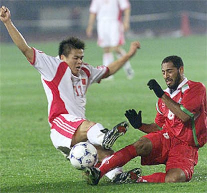 El chino Li Tie (a la izquierda) disputa el balón al omaní Al harbi en el partido de ayer en Shenyang.