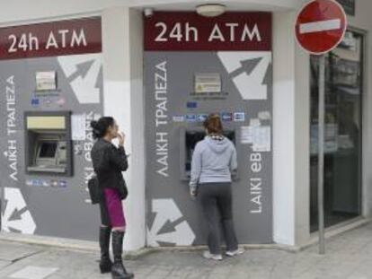 Dos mujeres sacan dinero de un cajero de una sucursal cerrada del Banco de Laiki, en Nicosia, Chipre, hoy martes 19 de marzo de 2013.