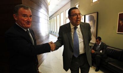 Juan Ramón Avilés, presidente de la comisión de control de la CAM, a la izquierda, saluda al exconsejero José Enrique Garrigós, en las Cortes Valencianas.