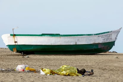 Uno de los migrantes, desfallecido, sujeta el móvil con el que viajaba en el cayuco en el que llegó a Canarias junto a otras 65 personas.