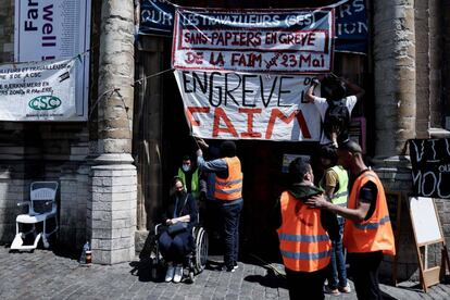 Un médico traslada a uno de los migrantes, débiles tras la huelga de hambre, al hospital. En la fachada de la Iglesia San Juan Bautista, un cartel que dice: "Los trabajadores sin papeles, en huelga de hambre desde el 23 de mayo".