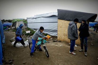 Uno de los pocos niños que hay en el campamento de Calais transporta un paquete en su bicicleta.