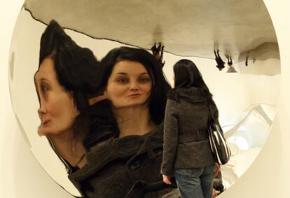 Una mujer se refleja en la obra 'Poniendo el mundo del revés', en la exposición de Anish Kapoor.