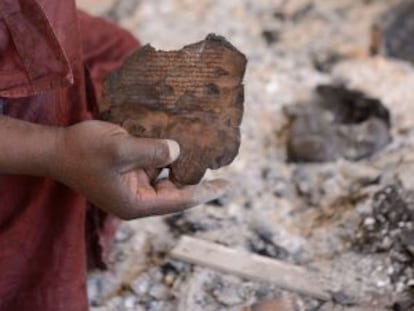 Un hombre muestra fragmentos de un texto quemado en el Centro de Documentaci&oacute;n de Ahmed Baba, en Tombuct&uacute;, el lunes tras la huida de los islamistas.