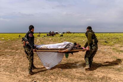 Dois membros das Forças Democráticas da Síria transportam um suposto combatente do Estado Islâmico em uma maca em 5 de março na província síria de Deir Ezzor.