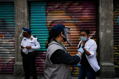 Una trabajadora entrega gel antibacterial a los peatones, en el centro de Ciudad de México.