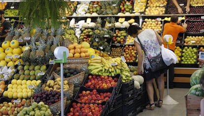 Una mujer elige fruta en un mercado.