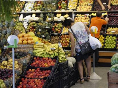 Una mujer elige fruta en un mercado.