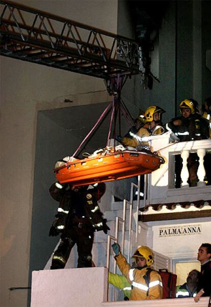 Los bomberos evacuan a un vecino cercado por el fuego (arriba).