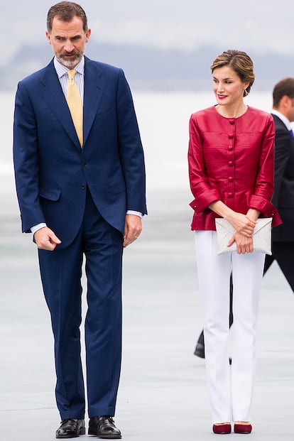 Otro ejemplo más de cómo combinar prendas de lujo con otras más sencillas. La Reina recurre a su chaqueta roja de Carolina Herrera (que ya llevado en varias ocasiones) y la luce con un sencillo clutch de Uterqüe.