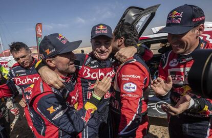 Carlos Sainz, recibe la felicitación de Stephane Peterhansel, izquierda y Nasser Al-Attiyah al final del Rally Dakar.
