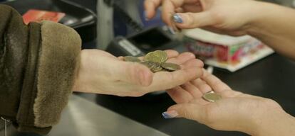 Una cajera ayuda a un cliente a contar las monedas en un supermercado.