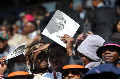 Varios asistentes se protegen del sol durante la conferencia 'Nelson Mandela' que rinde tributo a la figura del fallecido presidente sudafricano, en Johannesburgo, Sudáfrica.