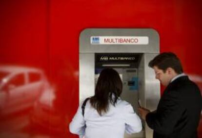 Una pareja saca dinero de un cajero automático, en Lisboa. EFE/Archivo