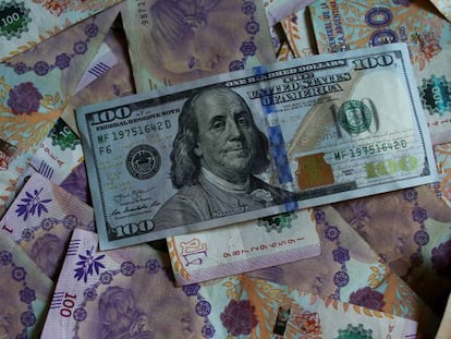 Un billete de 100 dólares estadounidense junto a billetes argentinos. 