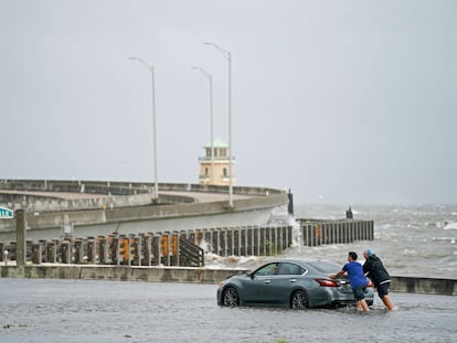 Dos hombres ayudan a un conductor varado en las inundaciones del 30 de agosto de 2021 en Biloxi, Mississippi.