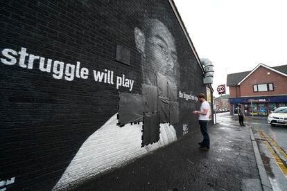 Un operario tapaba este lunes con cinta negra los insultos escritos en el mural de homenaje al jugador Marcus Rashford, en Mánchester (Inglaterra).